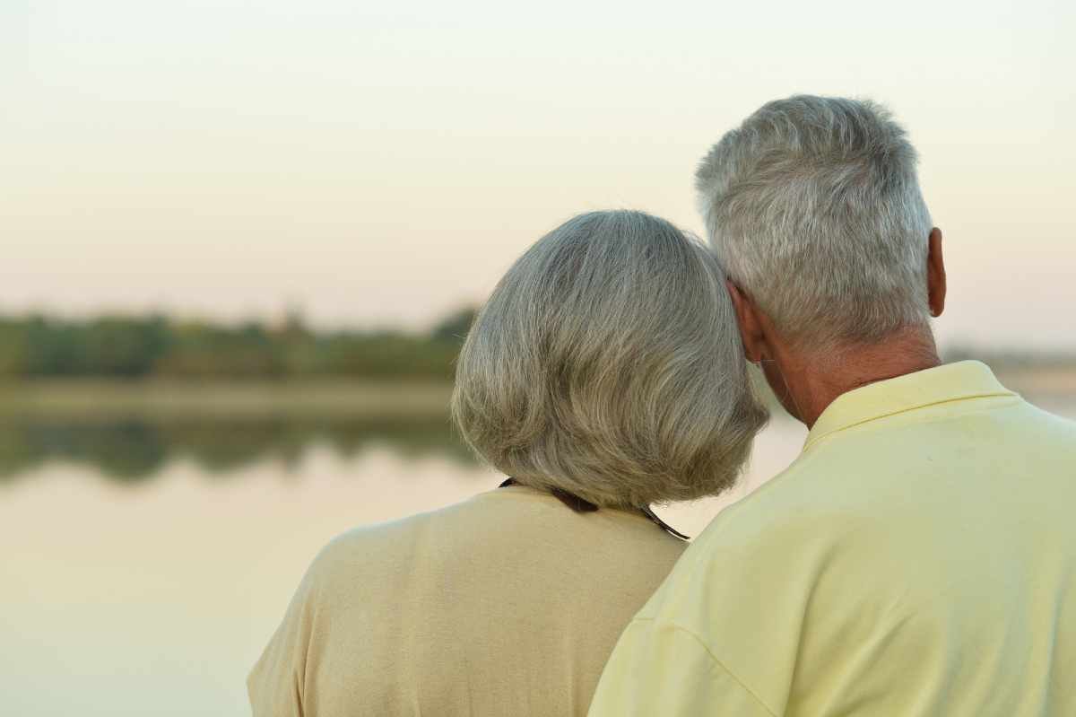 Happy senior couple near lake during sunset at summer