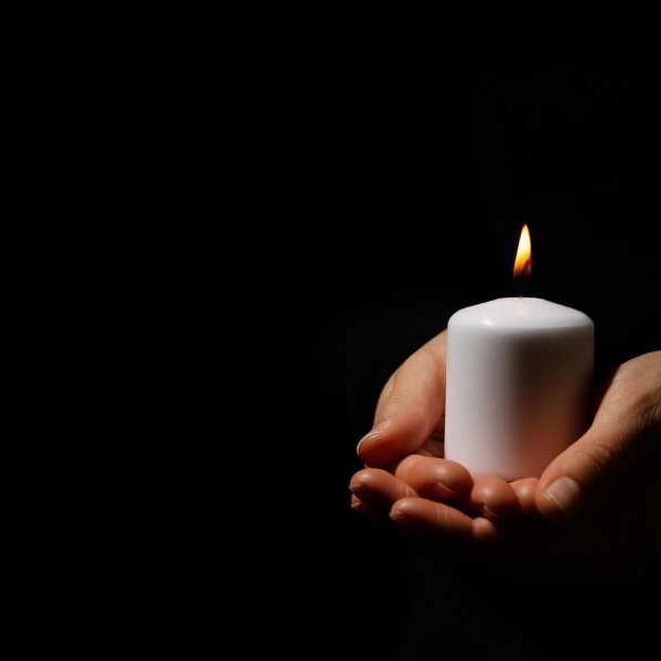 Woman holds candle on black